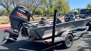 Grey Xpress aluminum boat in the parking lot attached to a trailer 