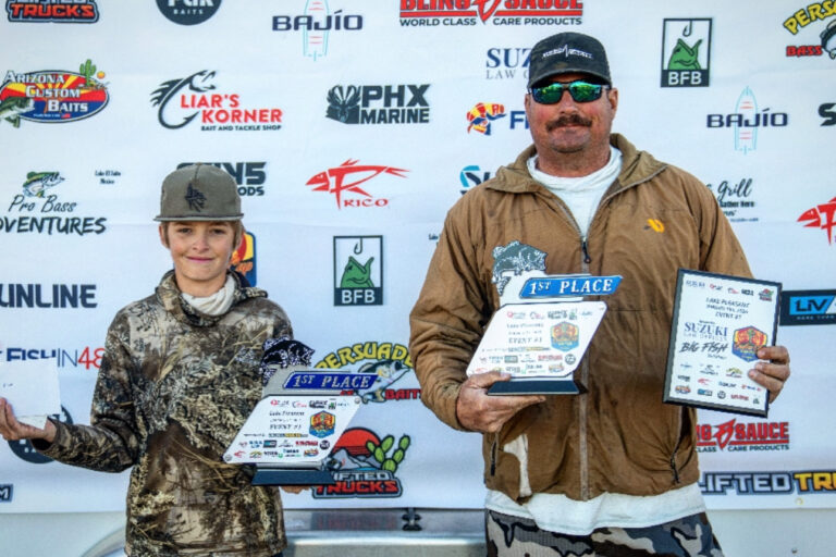 IMG_4976 Mick and Leland holding up their first place trophies in front of sponsor banner